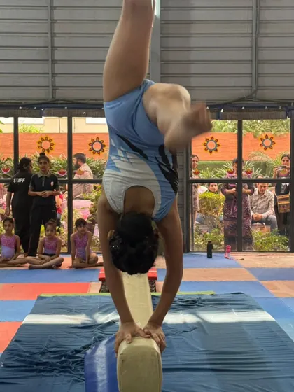 The focus and precision of a balance beam routine during a competition. This is what our gymnasts train for, performing with confidence in front of judges and an audience.