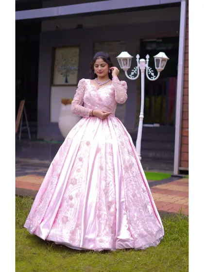 A model poses in the elegant pink gown, showcasing its flattering silhouette and intricate sleeve details. This is a perfect example of a modern, romantic occasion dress.
