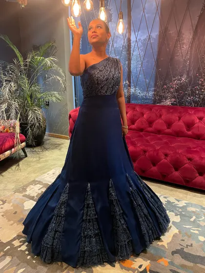 A full-length view of the dramatic blue cocktail gown, highlighting its unique silhouette and the intricate detailing on the skirt.