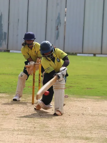 A batter plays a defensive shot, with the wicketkeeper watching closely. The image captures the technical aspects of the game.