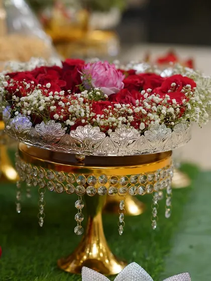 Another angle of the crystal stand with a floral arrangement, placed next to a traditionally dressed doll.
