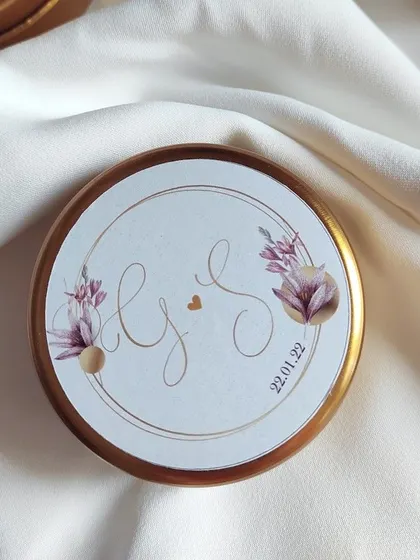 A close-up of a custom label for a wedding favor tin candle. I can design these with your initials, wedding date, and a floral motif to match your event's aesthetic.