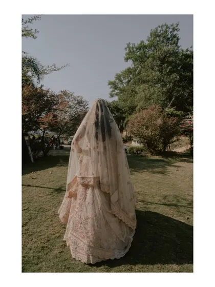 An artistic shot of the bride from behind, her entire form enveloped by her long, beautiful veil.