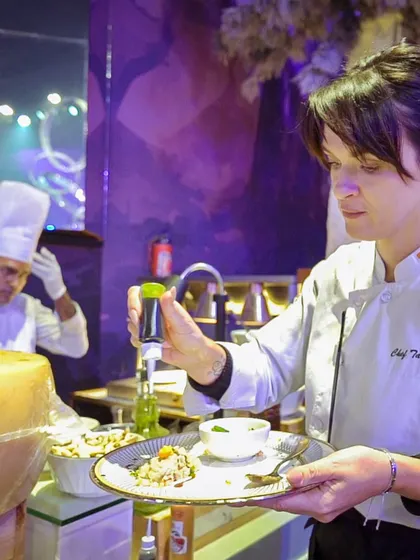 One of our international chefs, Chef Tatyana, adds a final drizzle to a pasta dish. Her presence highlights our diverse culinary team and our commitment to authentic global flavours.