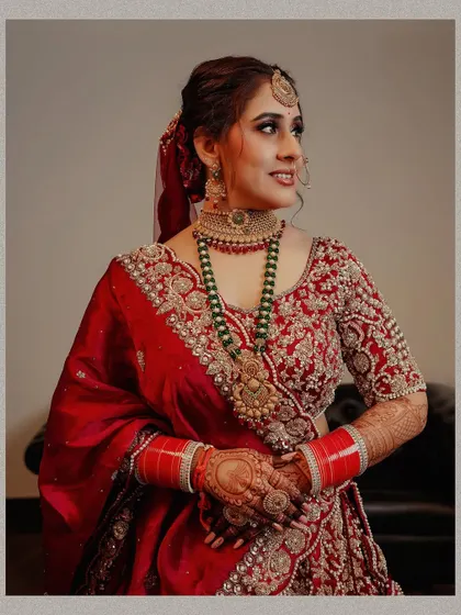 A classic three-quarter portrait of the bride, highlighting her intricate jewelry, mehndi, and the detailed embroidery on her blouse.