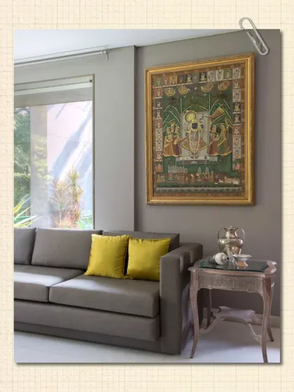 A traditional Pichwai painting, rich in detail and narrative, is given pride of place in a modern living room. By placing it against a neutral wall with minimalist furniture, the artwork's intricacy and color are brought to the forefront.