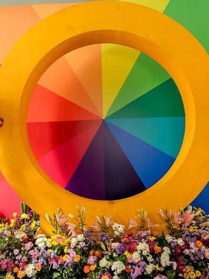 A 'color wheel' photo backdrop from the Carnival party, surrounded by vibrant floral arrangements. It’s a perfect spot for guests to capture fun, colorful photos.