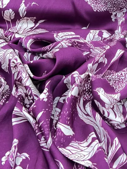 A rich purple modal satin with a bold white floral print, showcasing the fabric's beautiful drape and vibrant color.