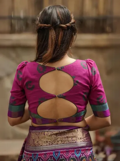 A unique back design with two circular keyhole cutouts on this magenta blouse. The puffed sleeves add to its distinctive style.