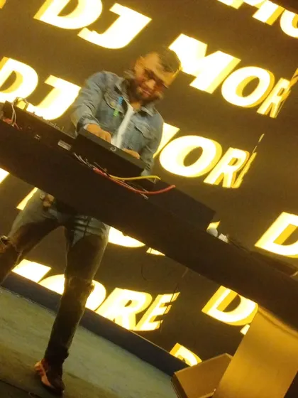 A dynamic, angled shot of me working the mixer during a high-energy set. The background visuals add to the electrifying atmosphere.