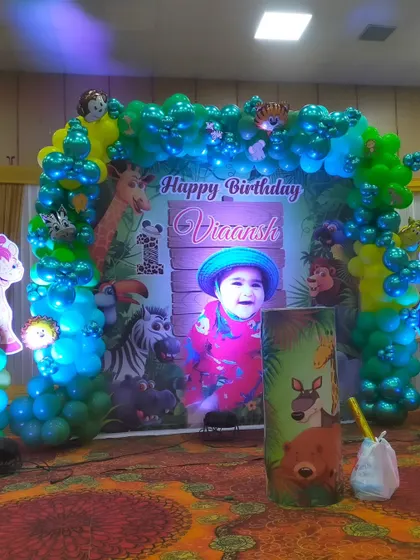 The main stage backdrop for the jungle party, featuring a balloon arch and a large personalized print.