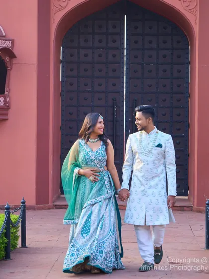 A candid moment captured as the couple walks hand-in-hand from the grand entrance of our pink palace set, dressed in beautifully coordinated traditional Indian attire.