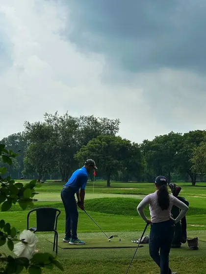 A couple practices together on the range under a cloudy sky. It's a perfect activity for partners to enjoy together.