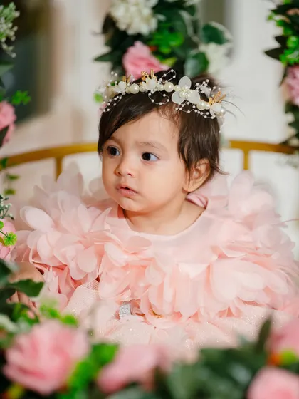 Another beautiful frame from the same session, capturing the child's innocent gaze and the delicate details of her floral crown and dress.