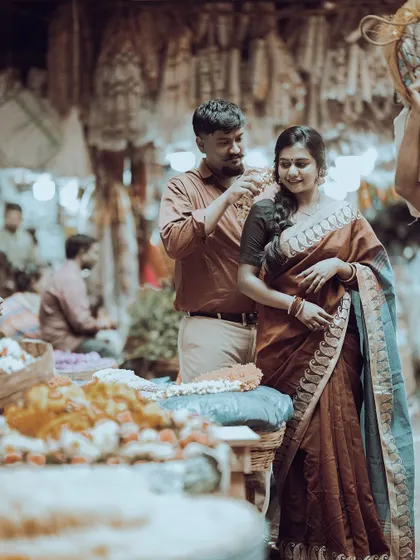 A tender moment in a bustling flower market, with the groom placing flowers in the bride's hair, capturing a slice of everyday romance.