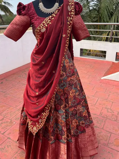 A maroon half saree with a printed skirt and an embroidered dupatta.