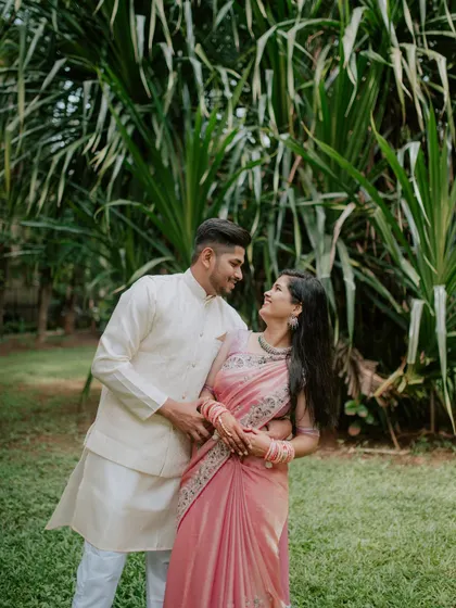 A romantic portrait of a couple looking at each other, surrounded by greenery.