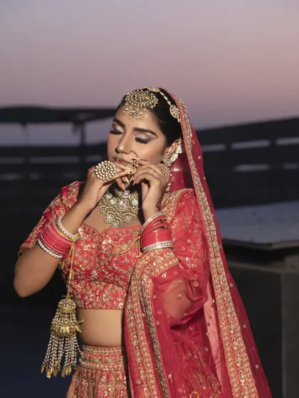 A candid shot of a bride with her hair in a secure bun, perfectly complementing her nath and other traditional jewelry. The style is designed to be both beautiful and practical.