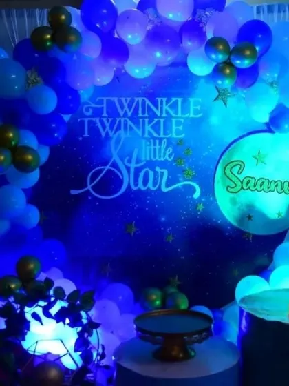 A "Twinkle Twinkle Little Star" theme is a classic choice for a first birthday. This setup features a celestial blue backdrop, star-shaped props, and a blue and gold balloon arch.
