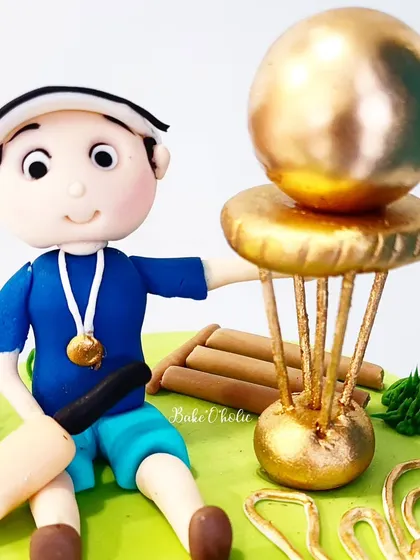 A close-up of the handcrafted figurine, complete with a medal and trophy. Personalizing cakes with details like this makes them extra special.