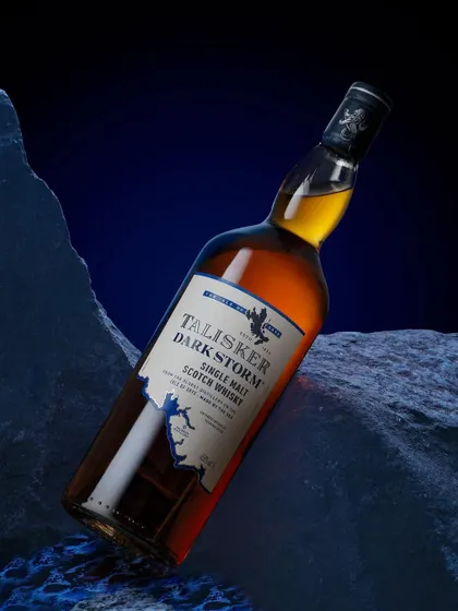 Talisker is "made by the sea," so I created this minimal set with dark, jagged rocks and a deep blue background to evoke a stormy coastline. The angled bottle adds a sense of drama and dynamism.
