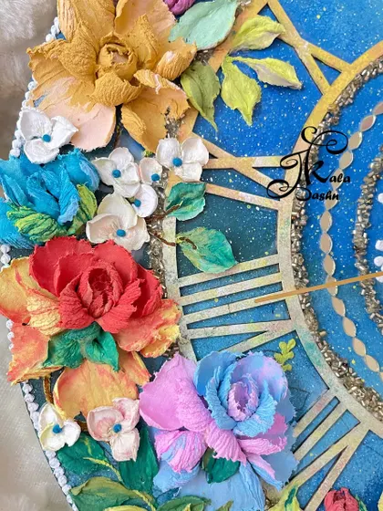A close-up of the flower cluster on the galaxy clock. You can see the different textures, from the smooth petals of the rose to the bumpy texture of the smaller blue flowers.