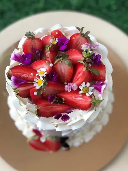 A beautiful cake topped with fresh strawberries and delicate edible flowers.