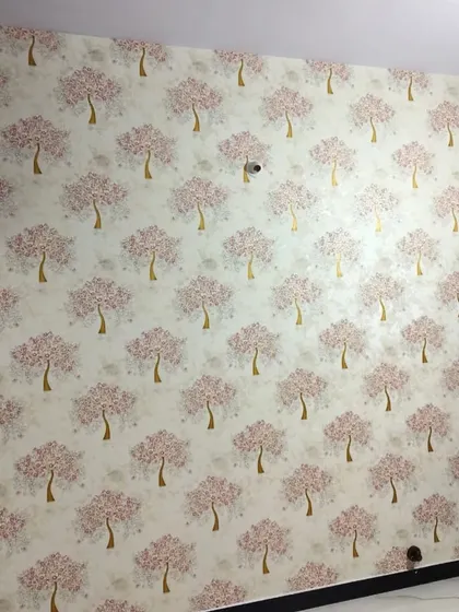 A repeating tree motif in soft pink and gold adds a touch of whimsy and warmth to this room. This type of patterned wallpaper is great for creating a consistent and charming look across a full wall.