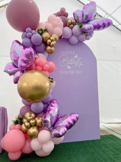 For a touch of modern elegance, we designed this "A Little Butterfly is on the way" theme. It features a custom lavender arched backdrop, adorned with an organic balloon garland in shades of purple, pink, and gold, and accented with large, shimmering butterfly foils.