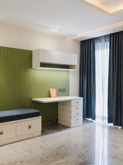 A magical kids' room with an olive green accent wall, a built-in study desk, and a cozy seating nook with storage drawers underneath.