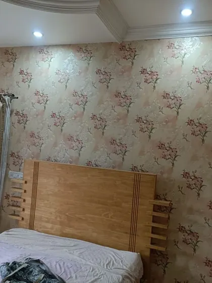 A soft pink cherry blossom wallpaper creates a romantic and serene atmosphere in this bedroom. The design is perfect for an accent wall behind the bed.