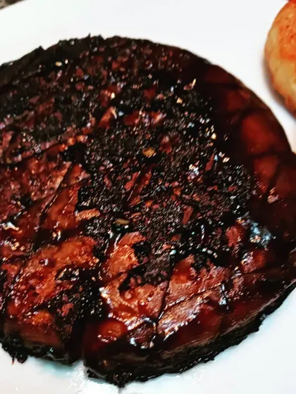 A well-done portobello mushroom steak, charred on the outside to develop a deep, smoky flavour.