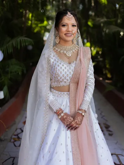 A full-length shot of the bride in her white lehenga, looking radiant and ready for her special day.