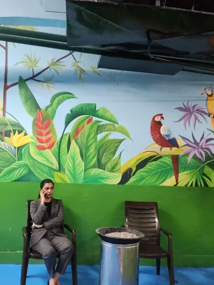 A closer look at the parrot illustrations within the Leela Hotel jungle mural. The bright colors of the birds stand out against the lush green foliage.