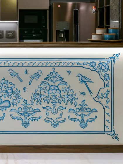 A detail of the hand-painted kitchen counter mural, showing the delicate birds and floral patterns. This close-up reveals the precision and artistry of the craftsmen, whose work brings a personal and rooted story to the heart of the home.