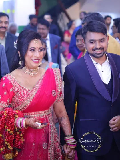 A candid photo of the happy couple during their reception entrance. The bride's makeup is fresh and vibrant, with pink tones that complement her beautiful lehenga.