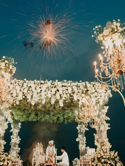 Fireworks light up the night sky over this stunning all-white mandap in Goa, complete with elegant chandeliers.