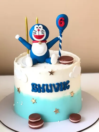 A dreamy Doraemon cake for a 6th birthday. This design features a handcrafted Doraemon figure sitting on a cloud-like buttercream cake.