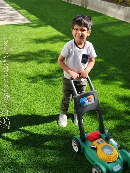 Enjoy a perfect green lawn all year round. This child playing with a toy mower shows just how much fun and how little work our artificial grass is.