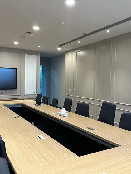 Looking down the length of the conference table, this shot emphasizes the room's capacity and formal layout. The central cutout in the table allows for concealed cable management.