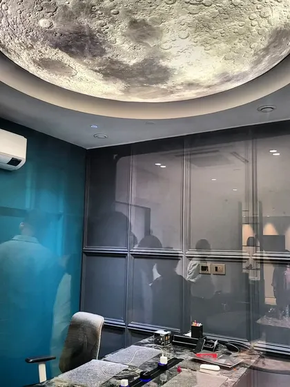Lighting can be a statement piece. This custom ceiling fixture, designed to look like the moon, provides beautiful ambient light and serves as a unique focal point in this modern office space.