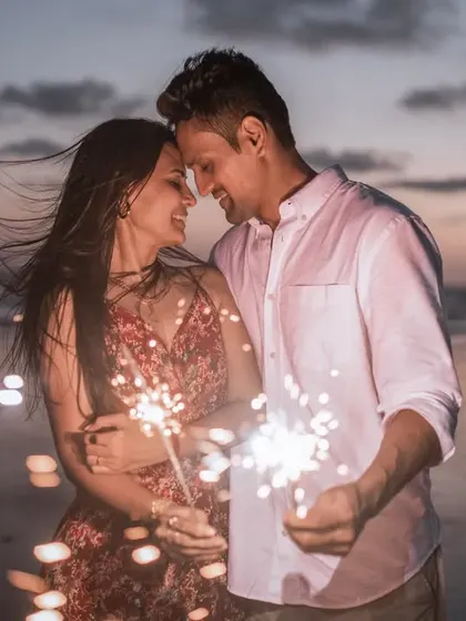 An intimate portrait of a couple with sparklers, the warm light illuminating their faces.