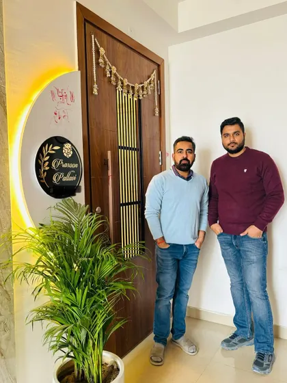 A happy moment with a client at their new home's entrance. The design includes a modern wooden door with a metal inlay and a beautiful backlit nameplate.