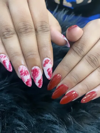 A dramatic set combining solid glossy red nails with red and white marble-effect accent nails on a stiletto shape.
