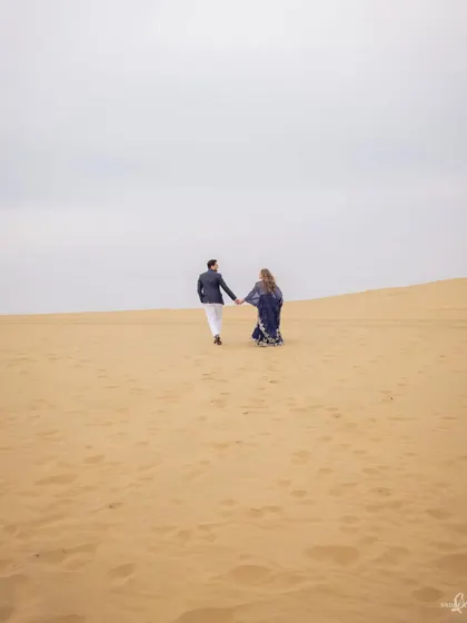 Priyangi and Kishan walk across the vast sand dunes of Jaisalmer. This epic, wide shot captures a sense of adventure and the beginning of their journey together.
