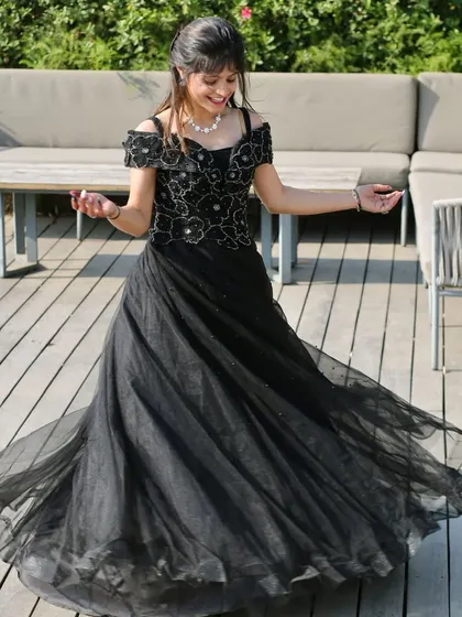 A joyful spin in a gorgeous black ball gown. The off-shoulder design and full tulle skirt create a look that is both classic and modern.