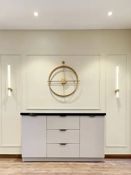 A classic and elegant statement wall created with simple wall molding and a large, decorative clock flanked by modern sconces.