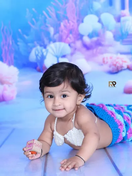 A happy baby mermaid plays with a toy, fully immersed in her magical underwater world. These sessions are designed to be fun and engaging for your little one.