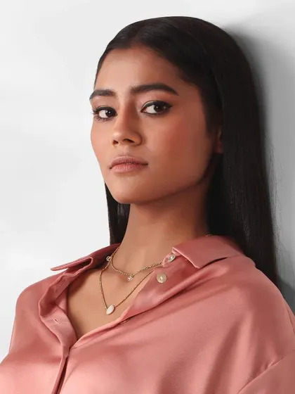 This beauty headshot focuses on the model's strong, direct gaze and flawless makeup. The clean lighting and simple styling highlight her features, making it a powerful shot for her portfolio.