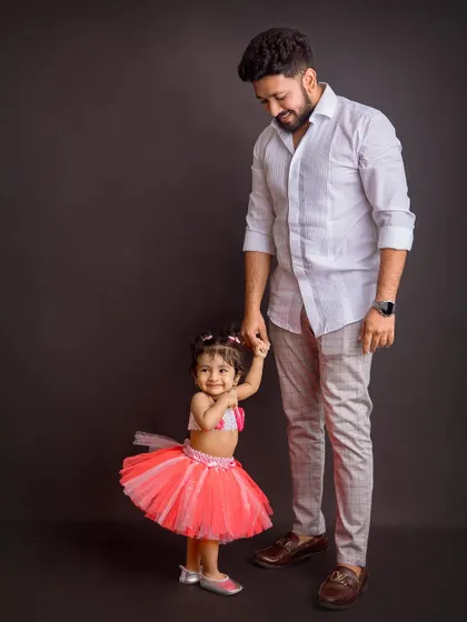A dad holding his daughter's hand. This full-length portrait captures a simple, loving interaction that speaks volumes about their connection.